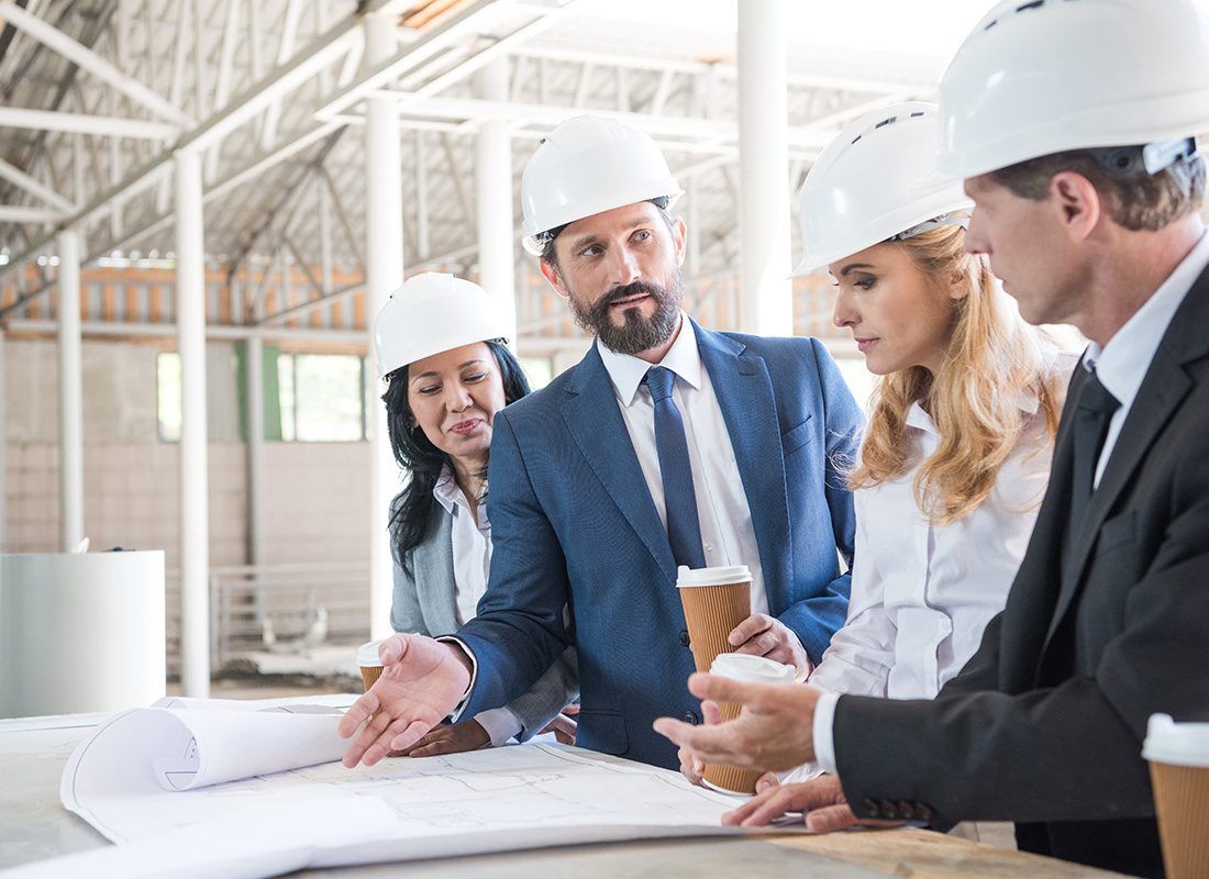 Insurance by Industry - Group of Construction Engineers Review Site Plans at a Project Site